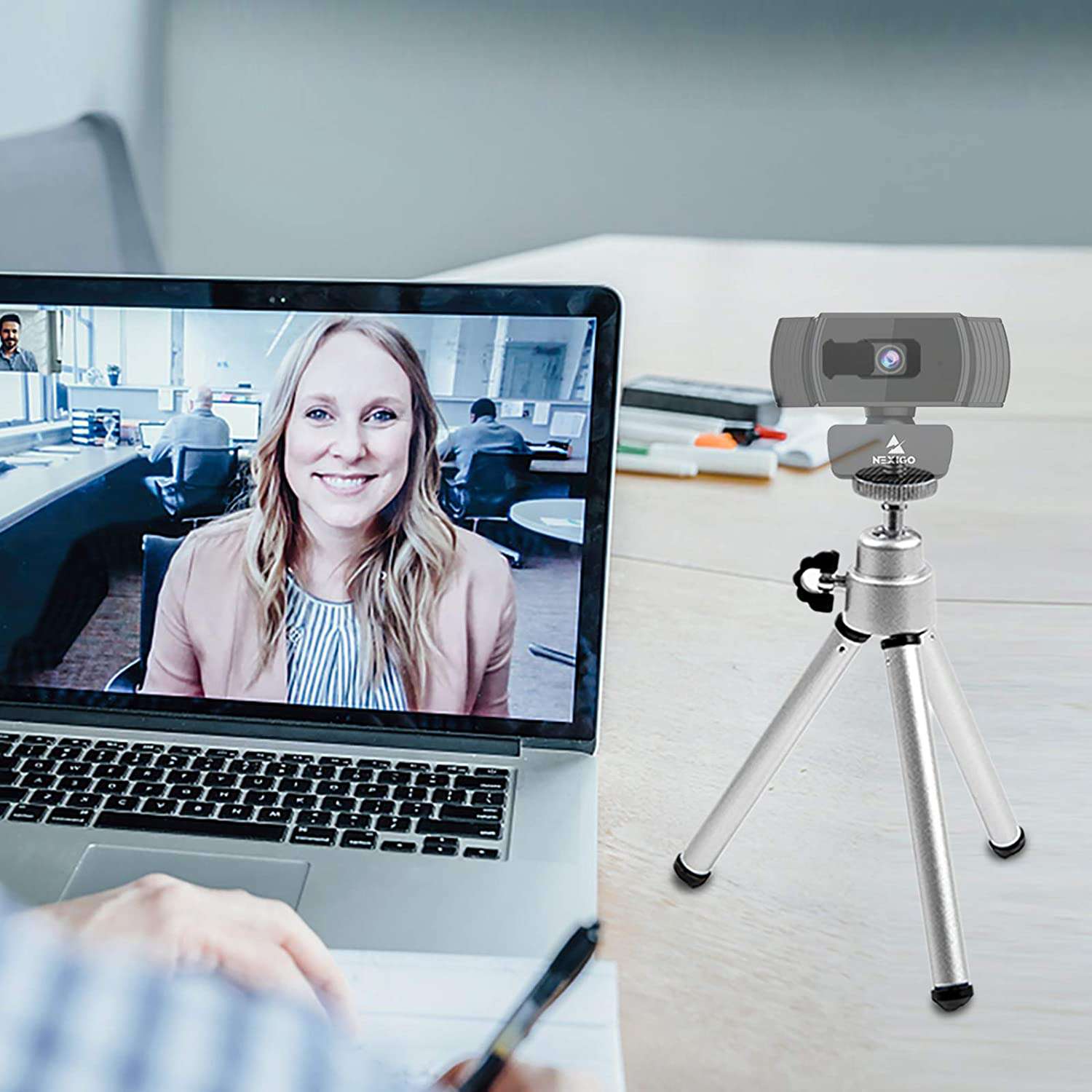 A man and a woman use the tripod to set up the webcam for a video conference.