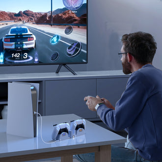 A man enjoys immersive PS5 gaming while the charging dock ensures the rest of the controllers are ready for the next game.